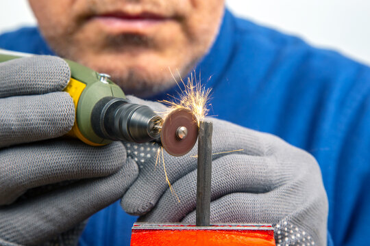 Worker processes metal with engraving drill close-up. The work of the dremel engraving electric tool. Industrial metal processing