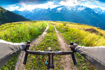 hands on the handlebars of a bicycle of a cyclist riding along a trail in nature. Point of view