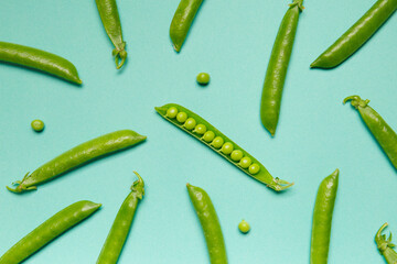 Fresh green peas in closed and open pods, pea grains are scattered on a green background, top view, studio photo.