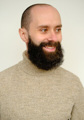 Fototapeta premium close-up male face, young pensive bearded and mustachioed man, satisfied guy with 30 years smiling and looks away, concept of human health, good mood, optimism