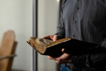 Close up shot bible. Alone male prayer reading old literature. Man in black shirt holding religious...