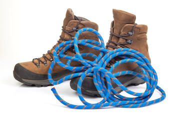 trekking boots for hiking next to a climbing rope on a white background. Travel and Hiking Equipment