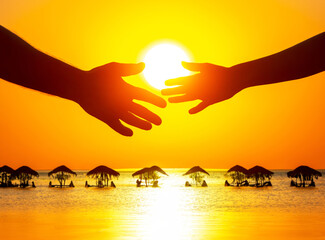 silhouette of male and female hands against the backdrop of the setting sun at an ocean resort. the concept of communication and the desire for intimacy in society and family