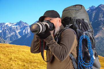 Fototapeta na wymiar bearded man tourist photographer with a backpack photographs the beauty of nature in the mountains. nature hikes in the mountains