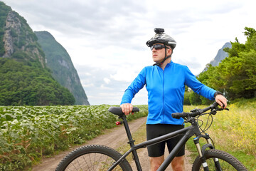 Fototapeta premium cyclist with Bicycle standing on field path.