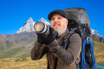 bearded man tourist photographer with a backpack photographs the beauty of nature in the mountains. nature hikes in the mountains