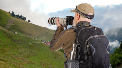 man tourist photographer with a backpack photographs the beauty of nature in the mountains. nature hikes in the mountains