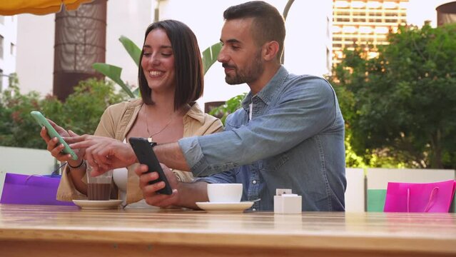 Sale, shopping, consumerism, leisure and people concept - happy couple looking at app on mobile phone shopping bags drinking coffee at shopping center