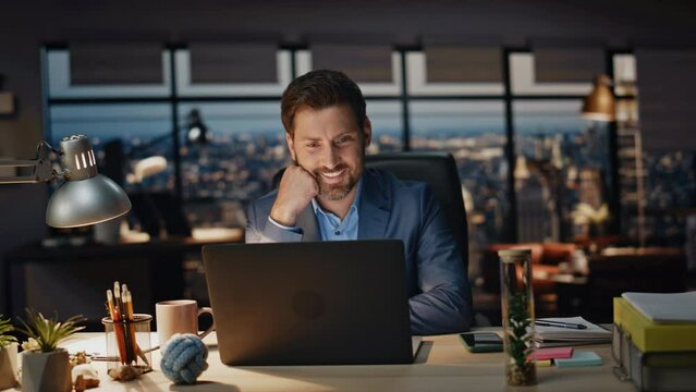 Happy manager reading computer in dark office closeup. Smiling man overworking