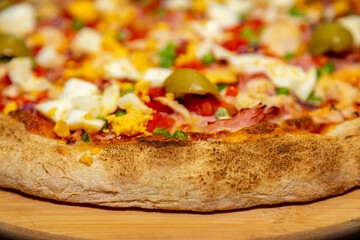 Traditional Portuguese pizza with ham, eggs, peppers, hearts of palm, tomatoes, onions, peas and cheese