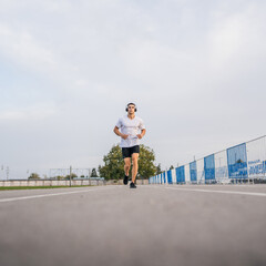 adult caucasian man jogging on the running track male athlete in stadium training run in sunny spring or summer day real people healthy lifestyle concept