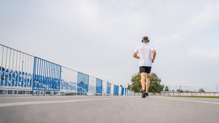 Obraz premium adult caucasian man jogging on the running track male athlete in stadium training run in sunny spring or summer day real people healthy lifestyle concept