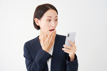 スマートフォンを持って驚く中年のビジネスウーマン　白背景