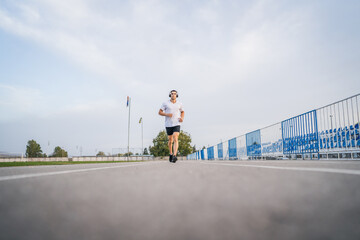 Obraz premium adult caucasian man jogging on the running track male athlete in stadium training run in sunny spring or summer day real people healthy lifestyle concept