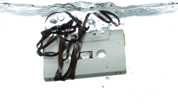 Cassette retro vintage Tape fall into clear water with air bubble. Black retro vintage cassette magnetic tape drop to wash old time. White background isolated freeze element