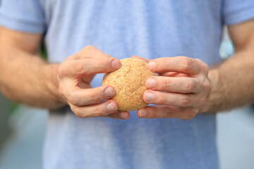 Man's hand holds mini bread, snack and fast food concept. Selective focus on hands with blurred background