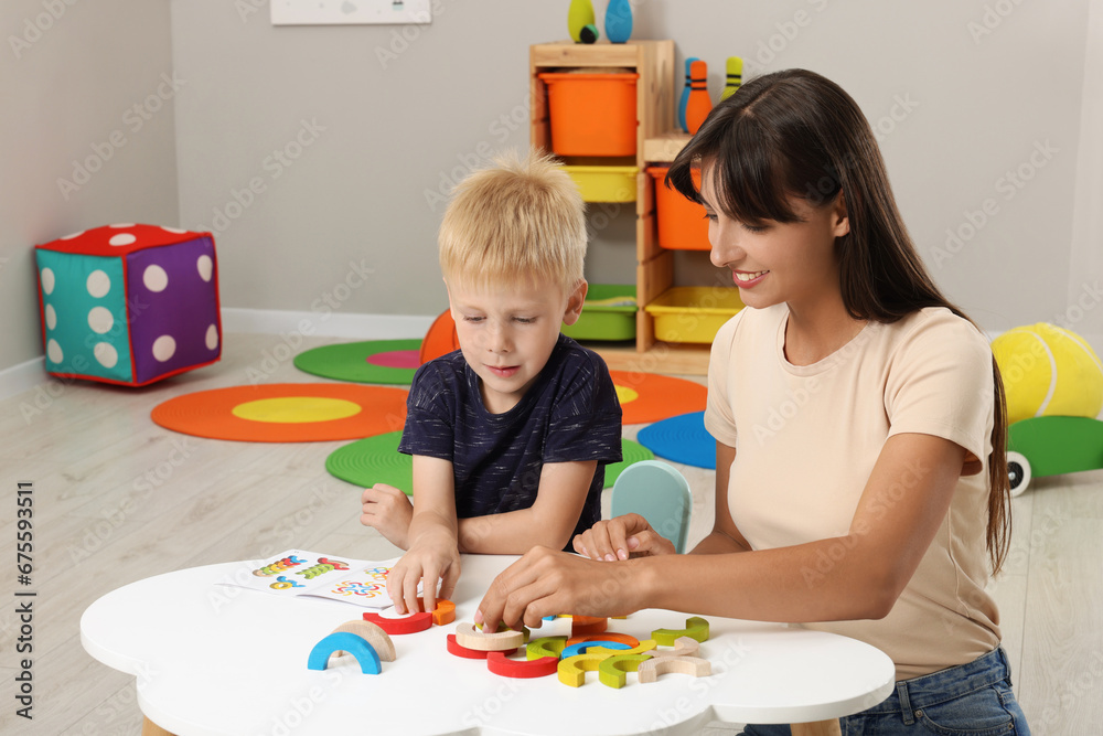 Sticker motor skills development. happy mother helping her son to play with colorful wooden arcs at white ta