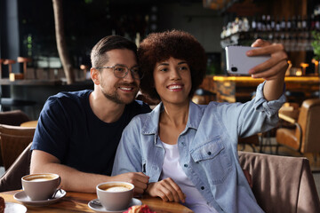 International dating. Happy couple taking selfie in cafe
