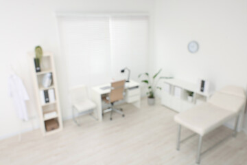 Blurred view of modern medical office with doctor's workplace and examination table in clinic