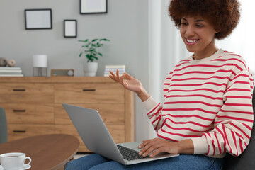 Beautiful young woman having video chat via laptop in room