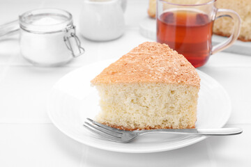 Piece of tasty sponge cake on white tiled table