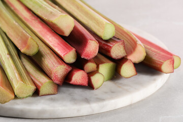 Fresh ripe rhubarb stalks on light grey table, closeup