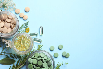 Different pills, herbs and flowers on light blue background, flat lay with space for text. Dietary supplements
