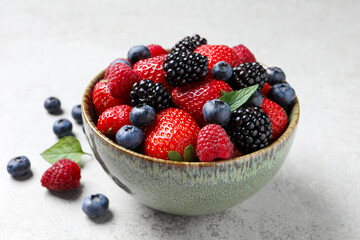 Different fresh ripe berries on light grey table, closeup