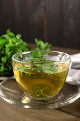 Aromatic herbal tea with parsley on wooden table, closeup