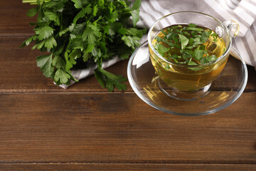 Aromatic herbal tea and fresh parsley on wooden table, space for text