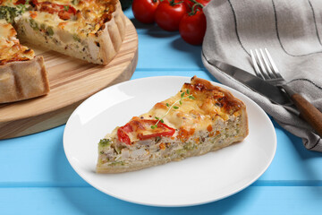 Piece of tasty quiche with chicken, vegetables, microgreens and cheese on light blue wooden table, closeup