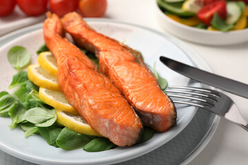 Healthy meal. Pieces of grilled salmon, spinach and lemon served on white table, closeup