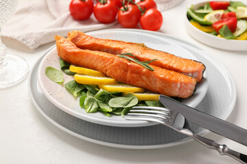 Healthy meal. Pieces of grilled salmon, spinach, lemon and rosemary served on white table, closeup