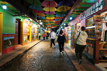 Obraz premium Street of the Umbrellas at night. Cobblestone street decorated with colorful umbrellas.