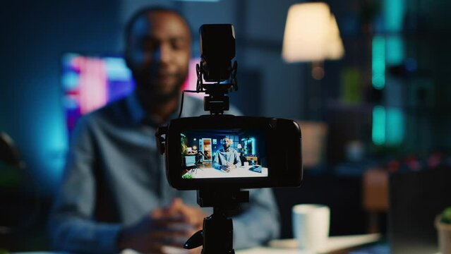 Close up shot on professional recording device in cozy home studio used for filming film video intro for online streaming platforms. Influencer in blurry background greets fanbase, focus on camera