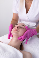Obraz na płótnie Canvas Female Patient Receives Spa Facial Massage Treatment In Spa Salon. Relax And Stress Relief. Professional Skin Care Therapist Takes Care Of Woman. Top View. Vertical Plane,