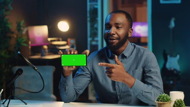 Content creator in studio films newly released green screen smartphone video review for tech enthusiasts. Viral online star hosts technology internet show, unboxing mockup cellphone