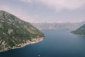 Sailing yacht sails along the Bay of Kotor with the coast of Perast in the background. Montenegro. Aerial view