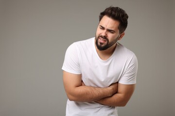 Young man suffering from stomach pain on light grey background
