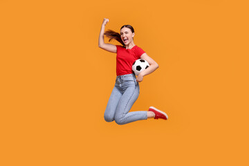 Emotional soccer fan with ball jumping on orange background