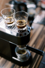 Fototapeta na wymiar Glasses with black coffee stand on a carob coffee machine