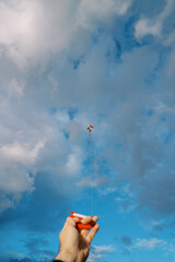 Man holds in his hand a spool of colorful kite string soaring in the sky