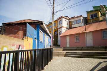 VALPARAISO, CHILE - AUGUST 13, 2016: Colorful houses in the streets and alleyways of Valparaíso. Graffiti on the walls, and a power post with a lot of messy wires can be seen as well.