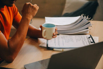Satisfied caucasian successful guy, freelancer or ceo, relaxes at workplace with legs thrown on table. Stylish guy uses laptop, browses the Internet, looks for ideas for a project, sitting at the desk