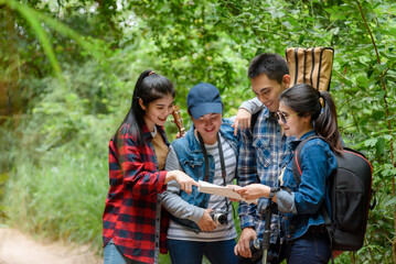 Group of friends walking on an adventure in the forest Look at the map to explore the forest and plan as a team.