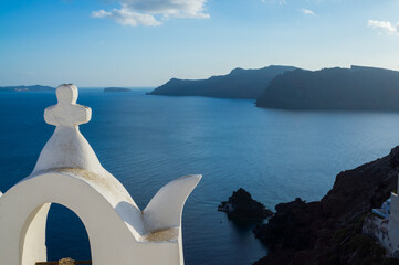 White church overseeing panoramic view of  volcanic caldera in Oia town, Santorini Island, Greece