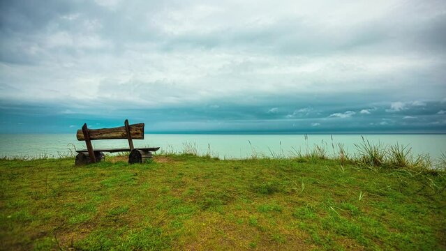 Waves of random thoughts and scenarios inundate the mind, creating a vivid mental picture of a wooden bench placed at the river's edge, as time swiftly passes along with the drifting clouds.