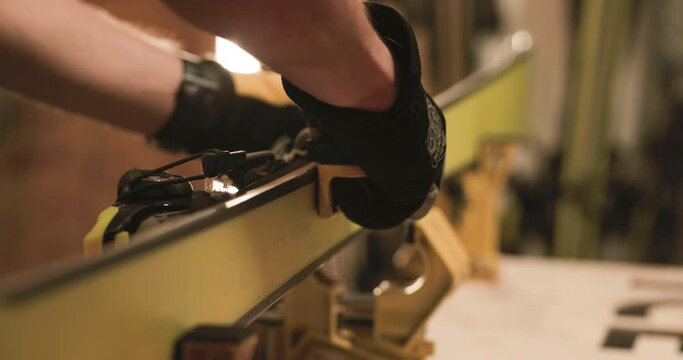 Man servicing skis. Abstract male hands working with special equipment on the ski edge. Close up video recorded with cinema camera.