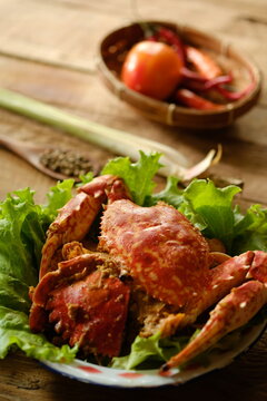 Rajungan Asam Manis, the crab is a popular seafood dish in the coastal area. The crab is served with tomato sauce, chili, lemongrass, lettuce and spices. Served on wooden table. Indonesian food.