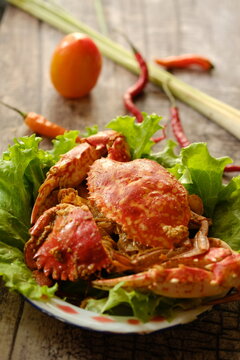 Rajungan Asam Manis, the crab is a popular seafood dish in the coastal area. The crab is served with tomato sauce, chili, lemongrass, lettuce and spices. Served on wooden table. Indonesian food.